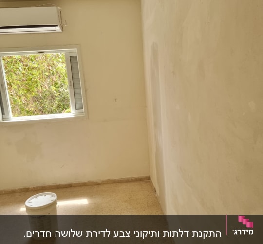 חדר עם קיר צבוע ודלי צבע על הרצפה